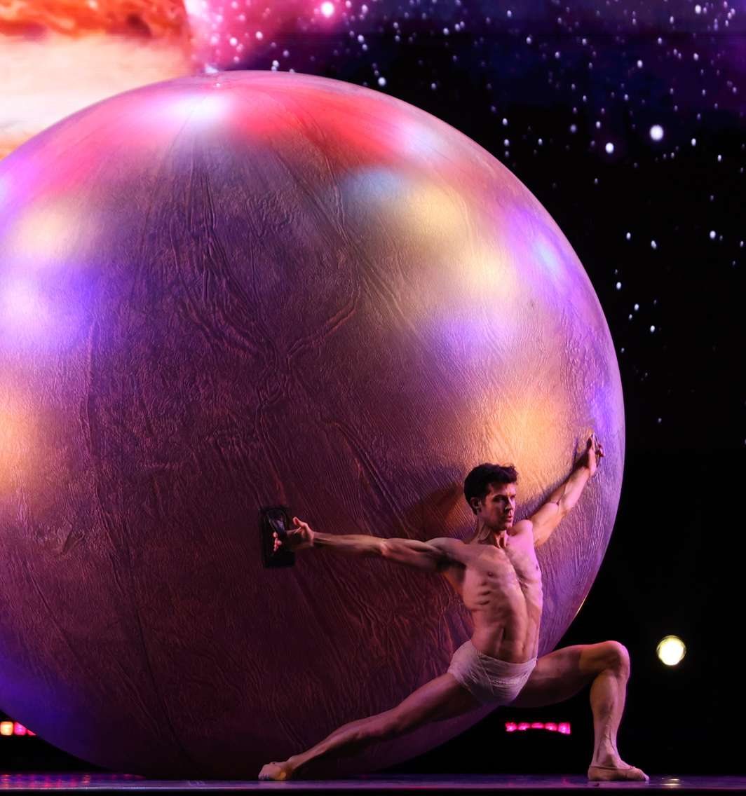 Roberto Bolle danza davanti a una grande sfera illuminata