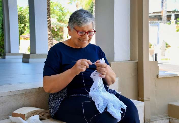 Una signora sarda lavora a maglia sotto un portico