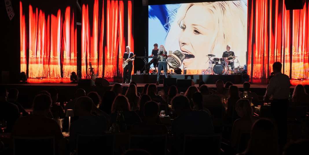 Una cantante sul palco davanti al sipario rosso