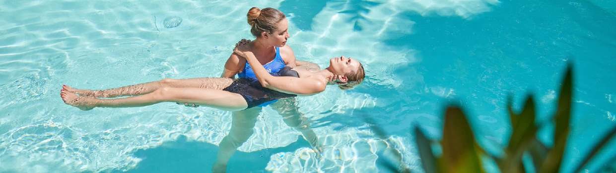 Una terapista accompagna un’ospite che galleggia in piscina